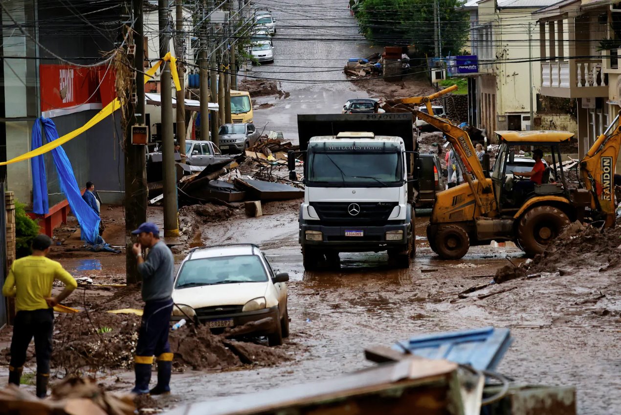 2024年5月11日，巴西南里奥格兰德州穆库姆，人们帮助清理洪水后部分被毁的房屋。